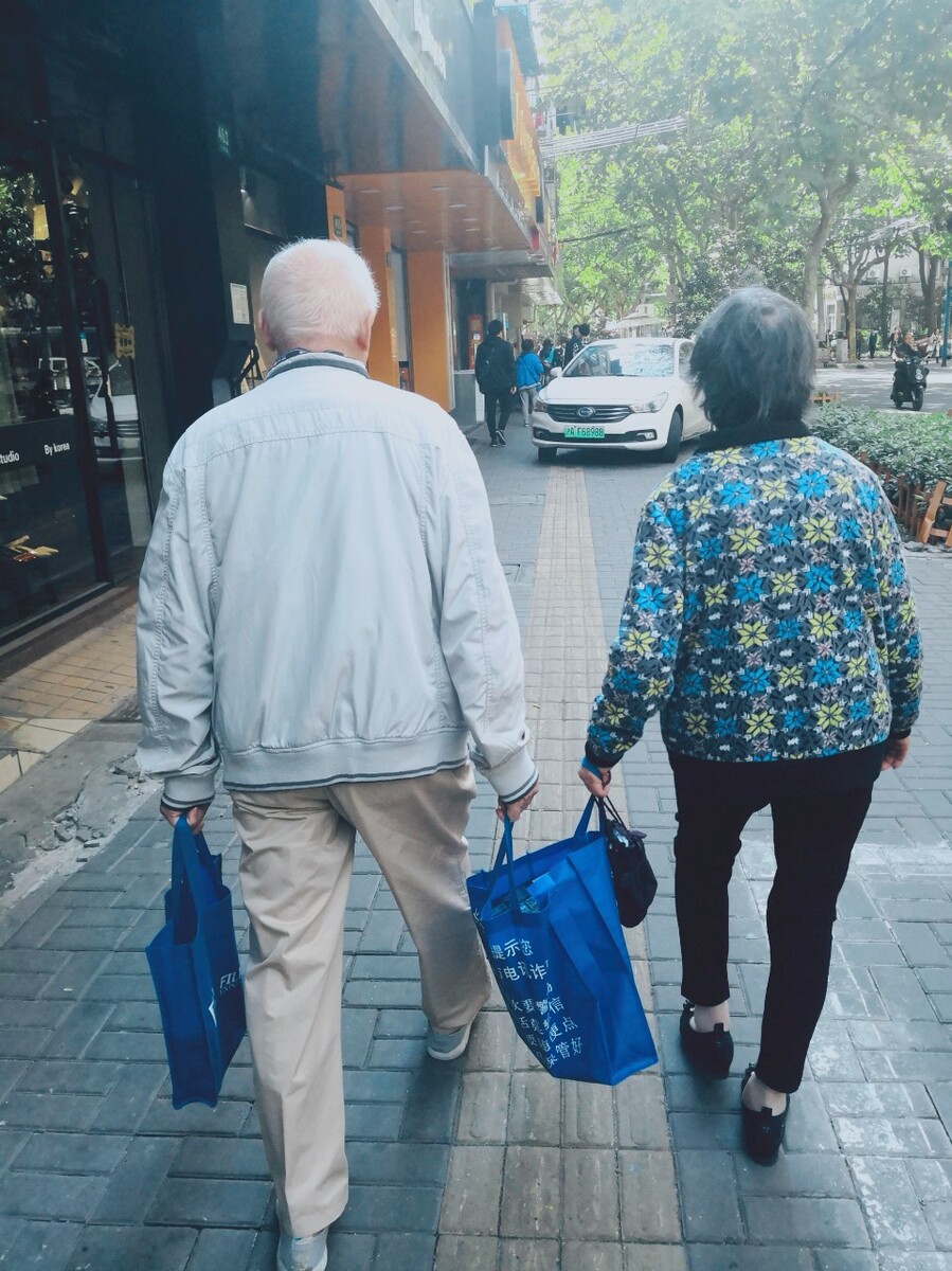 步履蹒跚的步伐,两人互相提一个袋子男人左手提一个袋子,两人也不怎么