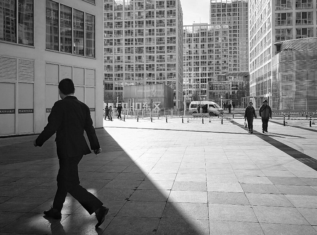 行走街头5——阳光里，阴影下。建外SOHO一个男人跨进楼宇的阴影，望着远处从阳光里走来的两个人，他们之间在这一阴一阳之间好似产生了奇妙的连接。