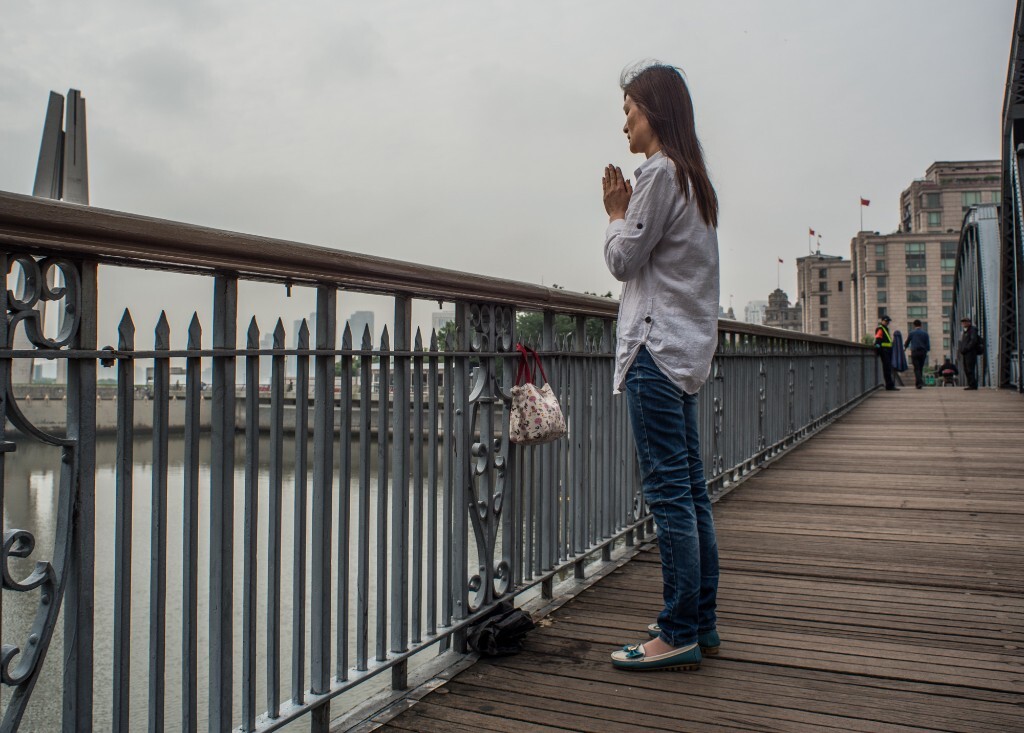 一女子独自在外滩外白渡桥上放生、念佛。