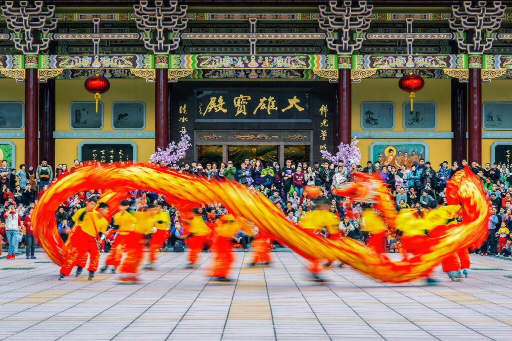 大雄宝殿前，一群人正在兴致勃勃地观看舞龙表演