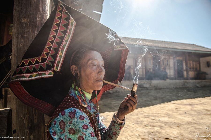 丽江老君山腹地，黑彝村落的老人在打扮完毕后，悠哉的点上了烟锅，开始享受早晨太阳带来的温暖。