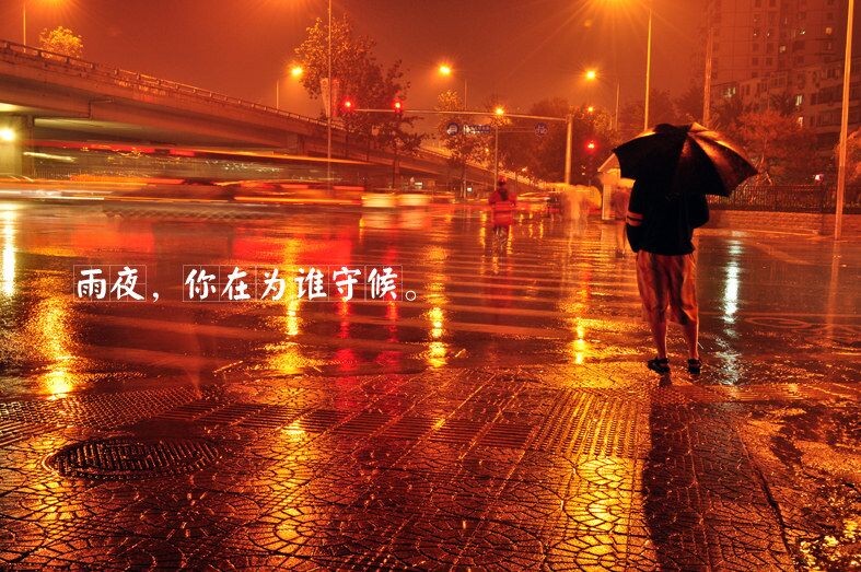 雨夜，你在为谁守候。<br />
刚才大雨倾盆，急匆匆的拿上相机和脚架，打着伞，站在十字街头，打着黑伞的陌生人成了画面的重心，他站在人行横道的这头，应该是在等待着一个人……。