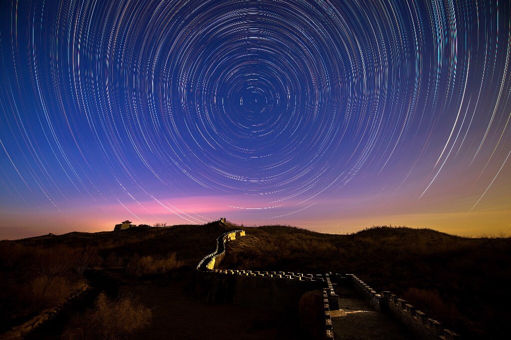 晴天的夜晚，满天星斗闪烁着光芒，像无数银珠，围绕着北极星不停地旋转。我坐在长城上，欣赏着这绚丽的夜空，记录着暗夜的美丽。拍摄结束之前初升的月亮照亮了长城，为画面增添了趣味。