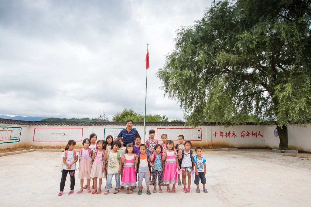 孩子们每人收到了一个捐赠的新书包,开心的和潘老师在操场合影留念。(有几个孩子只是暑假暂时在这上课)