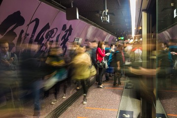 地铁中人们总是来去匆匆，画面中正好有个站立的红衣女子在流动的人群中形成明显对比。