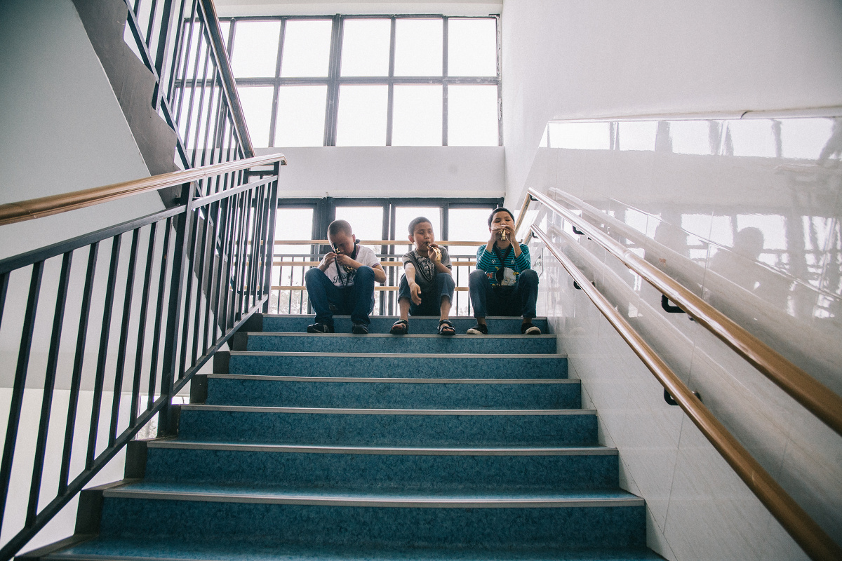 04.02 学校教学楼顶楼的楼梯,3个小孩在自己练习吹奏一种很短的乐器