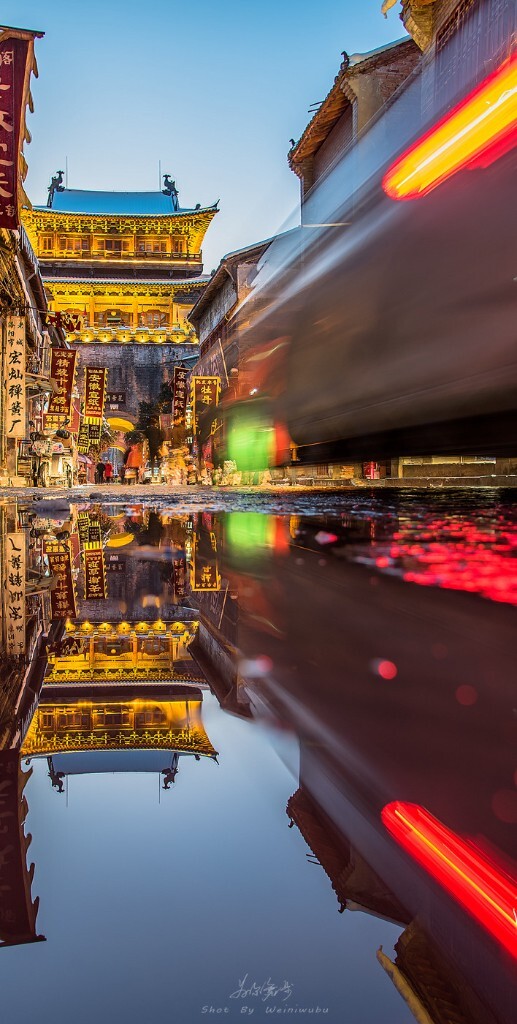 洛阳老城·丽景门<br />
(丽景门始建于隋代,于2002年修复。如今位于洛阳老城的最西段。通过路面的积水和行驶过得车辆,拍出倒影和车轨的画面。)洛阳老城虽然很有韵味,但规划还是略微杂乱了些,很多不协调的led灯牌让你无从下手,不过雪天的老城美景又确实不错,放弃总感觉可惜。最后还是一辆行驶的车辆,帮我解决了这一烦恼。