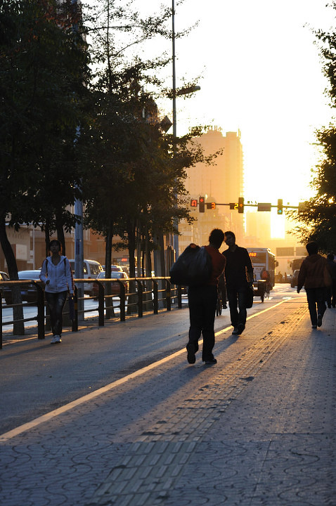 夕阳西下,背包客走在马路牙