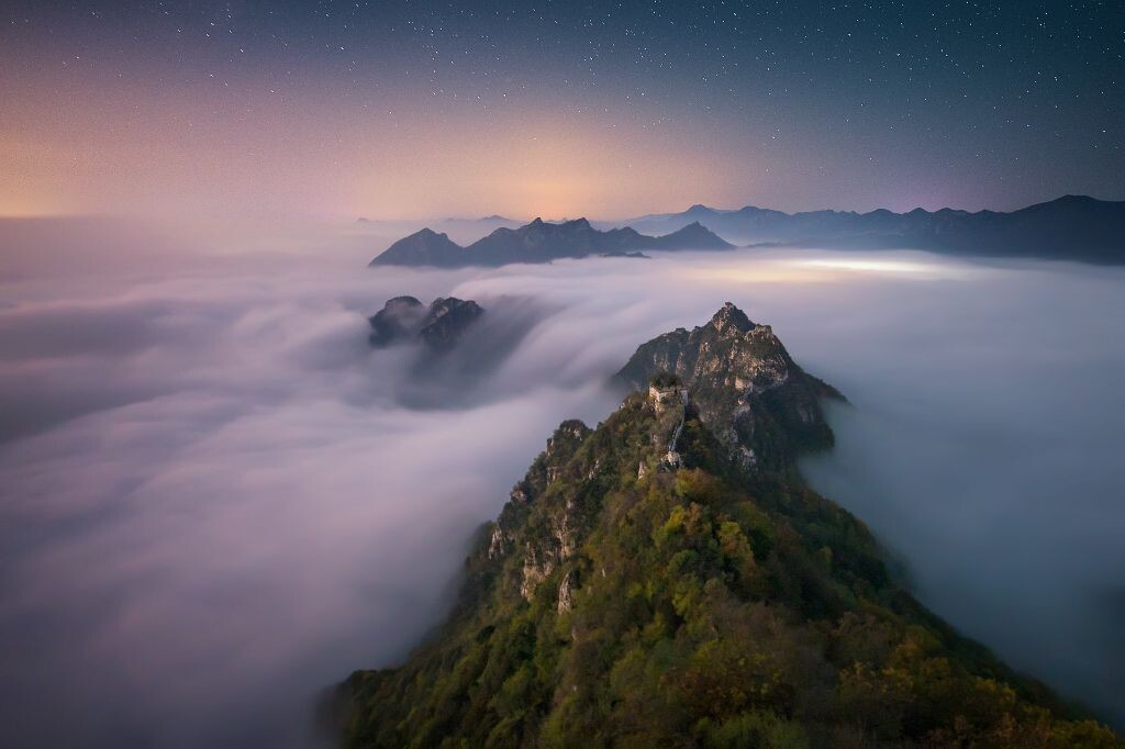 奔流<br />
云从山的凹口泄下,形成云瀑。落下的云则形成入海口常有的冲击扇。远处北京夜晚的灯光将云海照成梦幻的紫色。这一刻,磅礴与柔美相济。<br />
索尼A7S转接适马14art
