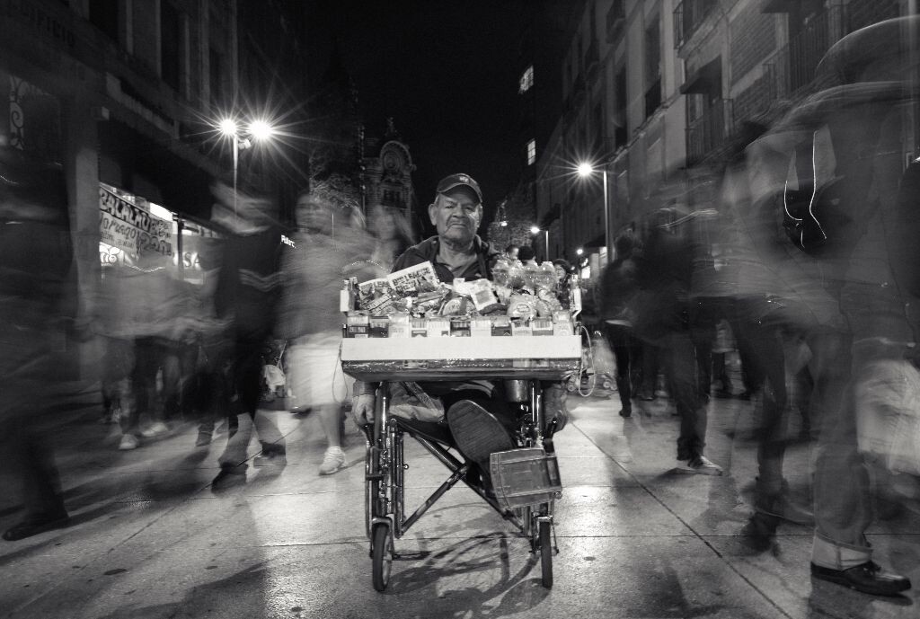 残疾的老人在繁忙的街上卖东西，很配合的让我照相。之后我买了点东西以示谢意
