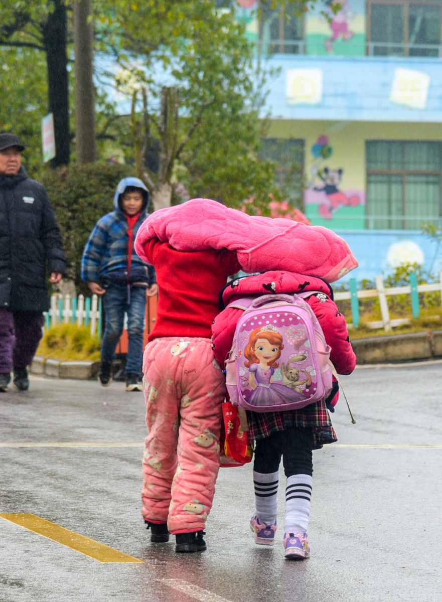 2019年1月拍于祁阳县书宛小学,两个孩子用棉衣遮雨一起回家.