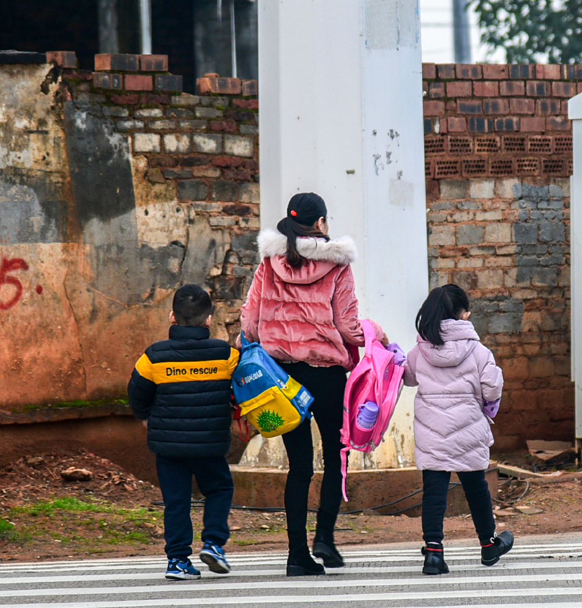 2018年11月19日拍于祁阳县明德小学,一位年轻的母亲为一双儿女提着