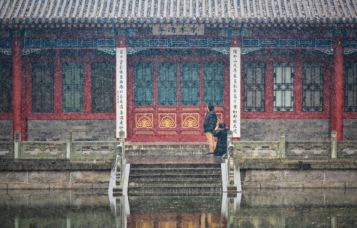 水木清华游客群之中的两位,在雪中用奇怪的姿势在拍着纪念照。来来回回折腾了好多次。