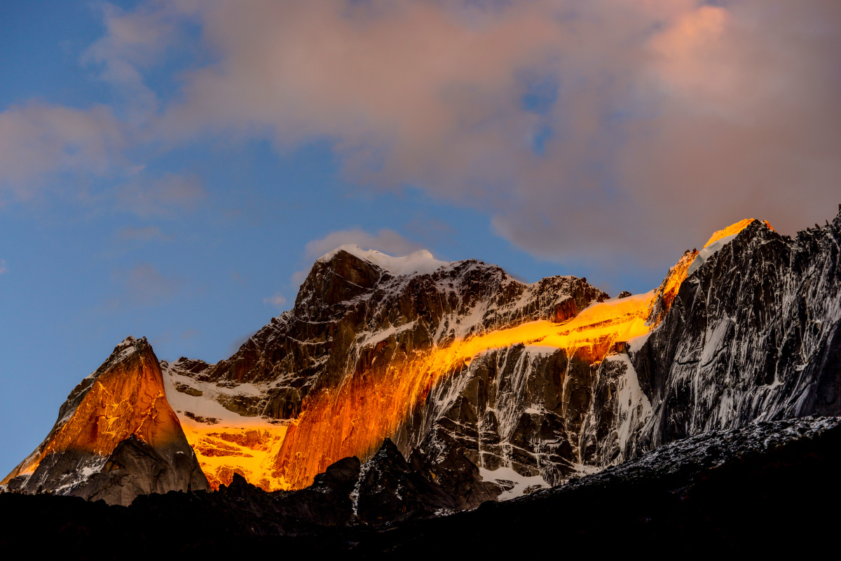 最后一缕阳光透过云层洒在四姑娘山西侧,犹如四姑娘山手捧一条金色的