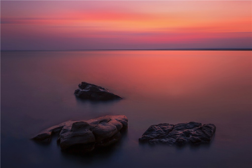 大海已经沉浸在浓重的夜色中，它那丰满而袒露的胸怀正在均匀地呼吸着，好象在消除白昼的疲劳。晚霞灿烂正当时，与海洋相遇在天际线。摄于防城怪石滩。