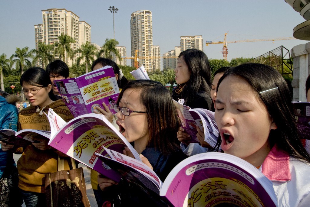 20.	2011年1月1日，广东省东莞市。打工者在广场大声朗读英语。她们利用业余时间，自费参加英语培训。