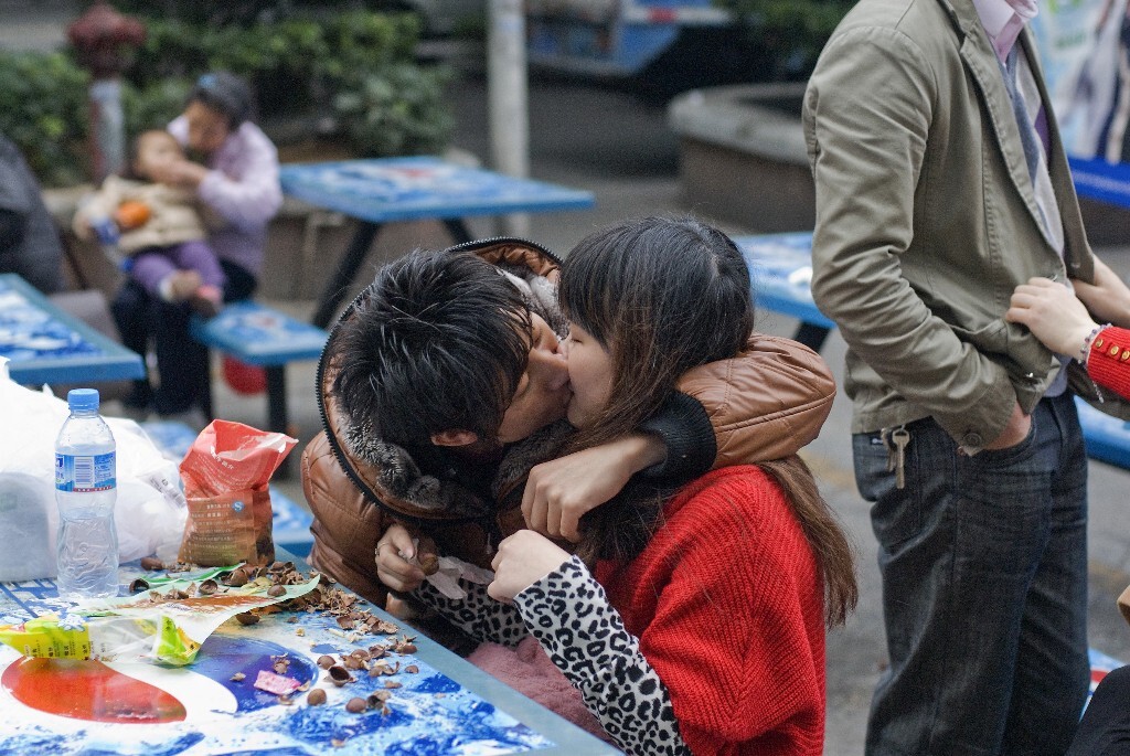 21.	2012年2月11日，广东省东莞市。两名年青的打工者在超市外拥吻。