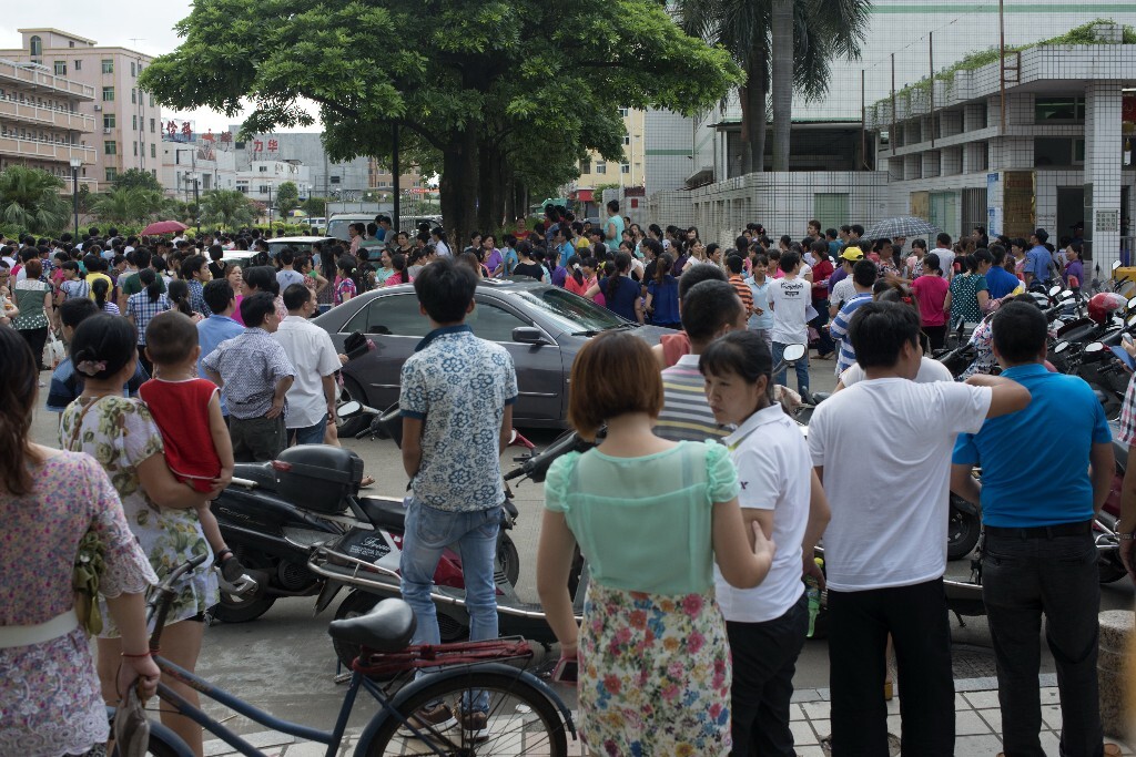 26.	2014年6月30日，广东省东莞市。工厂的老板跑路后，打工者们无奈地走出工厂，准备去上访。