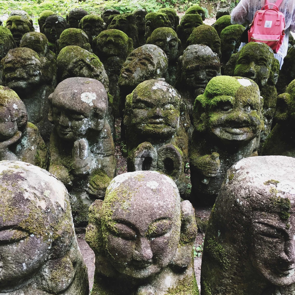 长满绿色青苔的佛像中出现了红色的背包,仿佛互相形成了点缀