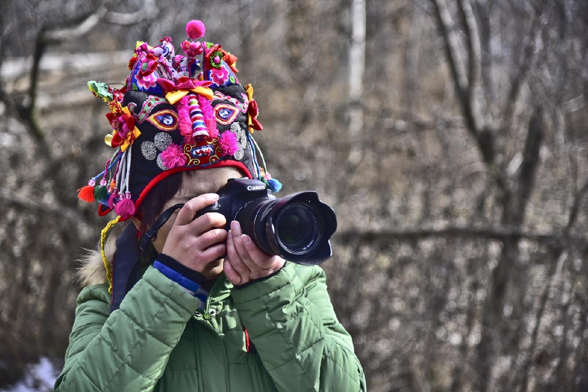 一位摄影爱好者带着当地特有的虎头帽特别醒目