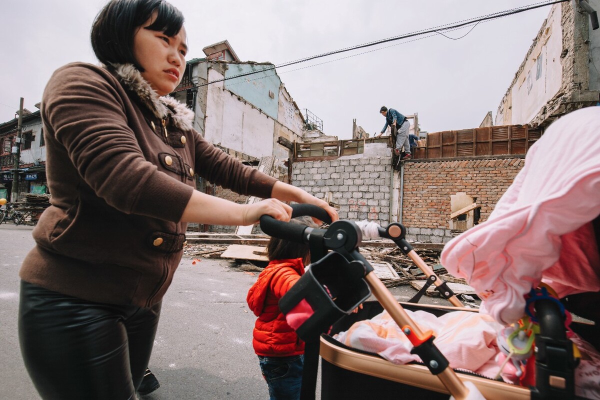 2016年4月2日，上海，杨浦区一位母亲带着两个孩子，从正在拆迁弄堂前经过。