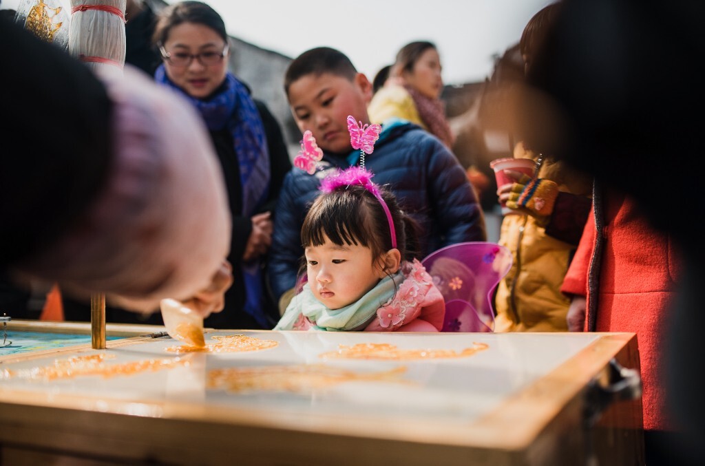 你还记得那时候吗 每次糖画师傅的周边都会围满人，可还是会拼命挤进去 ，在那个木质圆盘上 每个方向都有不同的动物， 你想转到自己喜欢的。 艺人用小汤勺舀起溶化了的糖汁，在洁白的石板上飞快地来回浇铸 。
