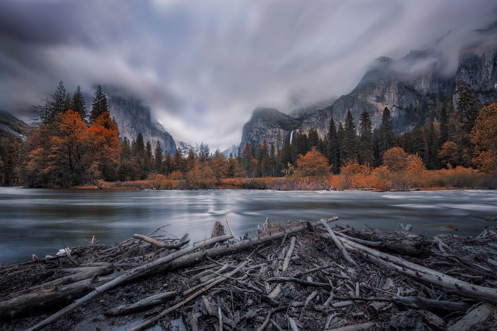 优胜美地 Valley View 秋景<br />
<br />
又是一个优胜美地的经典机位。这是第一天中午开车进优胜美地的第一个景点吧。天公不作美,云彩特别多,整个山被就像掉进了雾里,每走一步都感觉脚踩着雾似的。其实看过这个机位好多冬天的景色,山尖是白的,然后前景的石头和这块废木头也都覆盖成学,也是相当的好看。这张长曝虚掉水,模糊掉云彩和巍峨不动的山形成个对比,也算能看。<br />
<br />
说回正题,这又是优胜美地一个经典机位,叫Valley View. 其实是Tunnel View的下面,于是就有了水和糟木头的前景。还是简单介绍一下吧:左边的山是El Capitan, 是西班牙语中峭壁的意思。也是Mac OS X的名字。右边的山是Cathedral Rocks; 瀑布是Bridalveil Fall。当地的土著认为这个瀑布是整个优胜美地的入口,有邪灵守卫,进来的人一定不能看这个瀑布否则会有不好的事情发生。