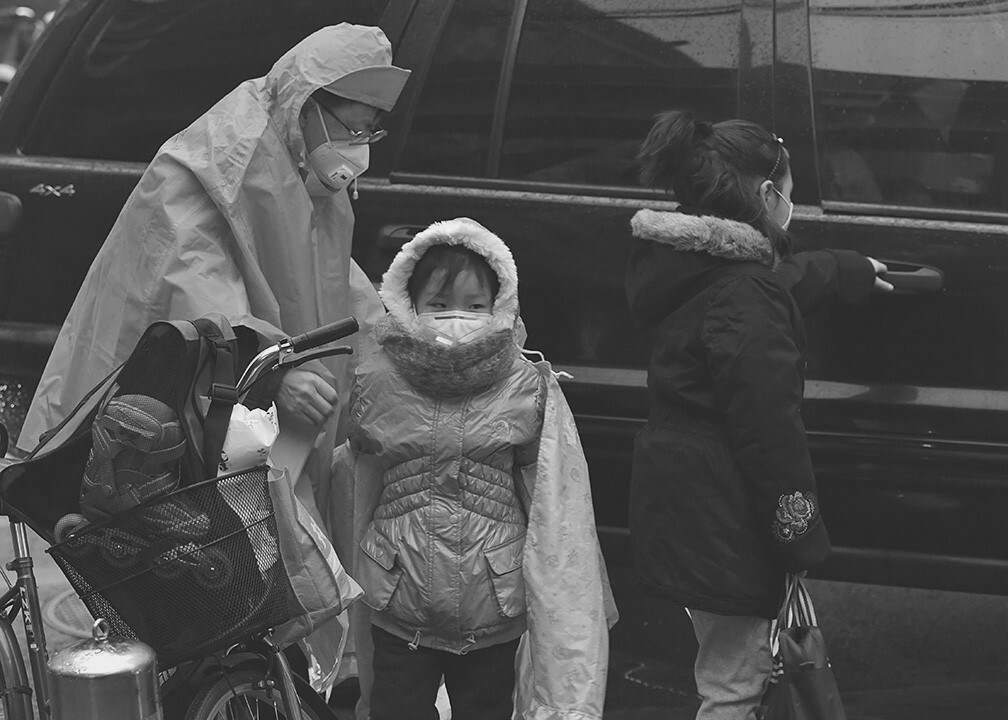 2015年12月14日7.42分,首次红色预警结束。中小学开课,在朝阳区实验小学门口,一位家长送孩子上学,而孩子被家长捂得严严实实。幼小的生命对与突然而来的雾霾也是似懂非懂,好像从出生开始,戴口罩就是她人生经历的程序。<br />