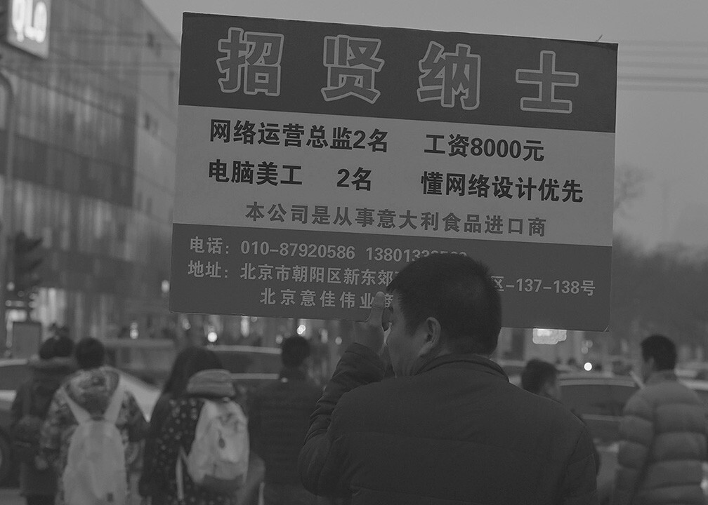 2015年12月19日16.56分,第二次红色预警。在体育场北路下班人群中,有人举牌招贤纳士,不少人停下脚步围观。<br />