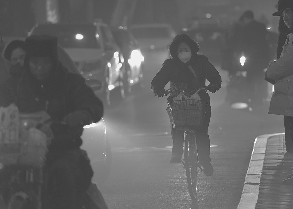 2015年12月22日17.45分,第二次红色预警。持续重度雾霾袭扰,城市空气质量明显下降,到处都是灰蒙蒙一片,能见度不足300米。 体育场东路,行人在拥挤的汽车空隙中穿过。