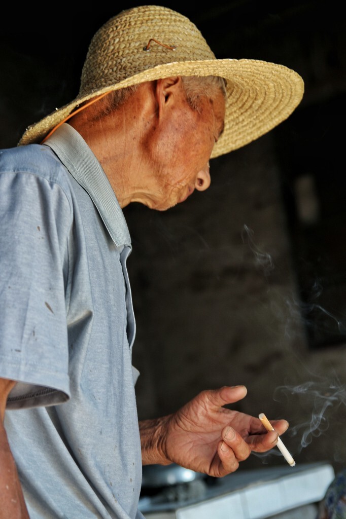 专注:爷爷点着了烟却一直在看着奶奶包粽子,忘记手中的烟了。