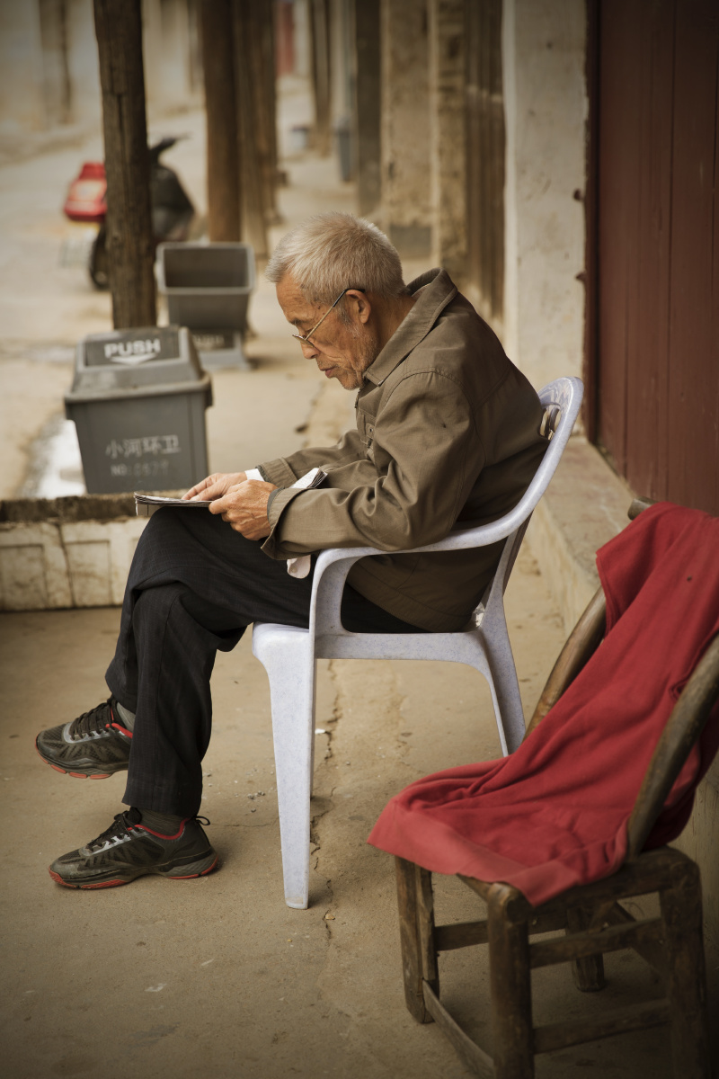 一位阿公在午后坐在自家门前看着今天的报纸,十分的安逸.
