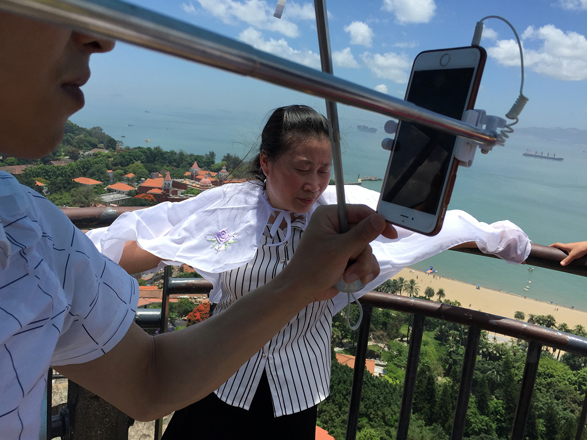 2016年6月19日,厦门日光岩,一个游客在另一个游客面前自拍.