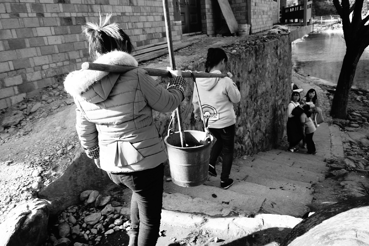 瑶里古镇,两名在外打工的年轻女子回家帮着挑粪水浇菜地