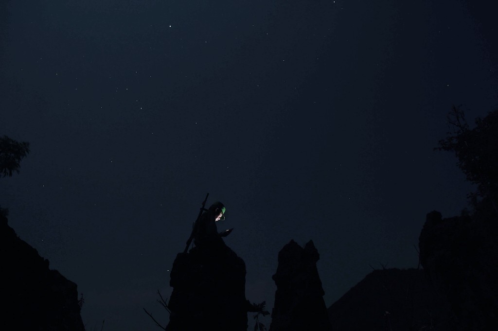 星辰漫天的夜空下,前线战场的一名士兵爬上陡峭的石头,搜寻更好的信号,给难民营里的家属报个平安