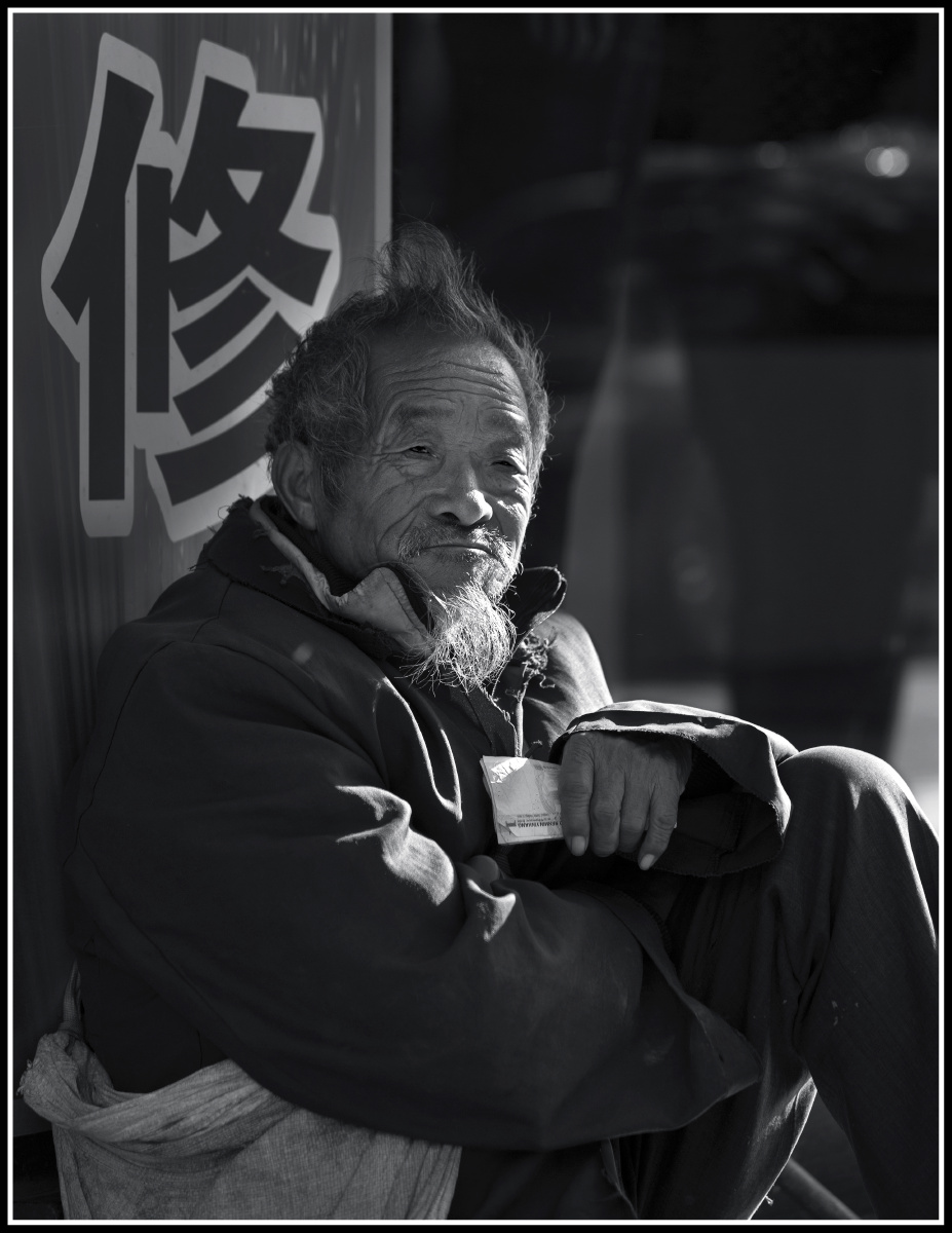 2015年12月17日,东莞,这位流浪的老人背着用米袋缝的背包在大街上行乞