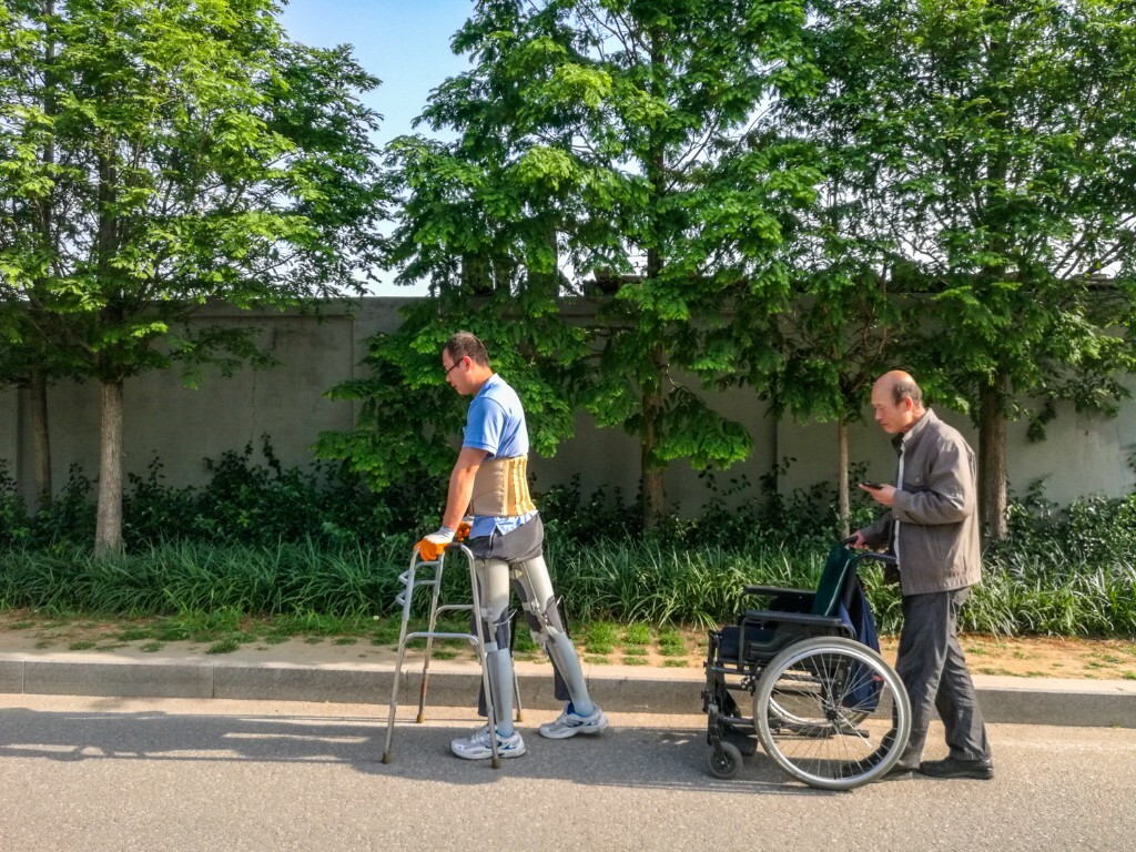 一位受伤的病人出院后每天早晨锻炼时他的父亲在后面推着轮椅陪同，他累的时候好坐在轮椅上休息。’
