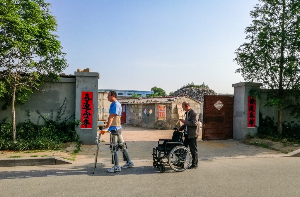 早上一位残疾人锻炼时父亲在后面陪同，体现出父爱如山。