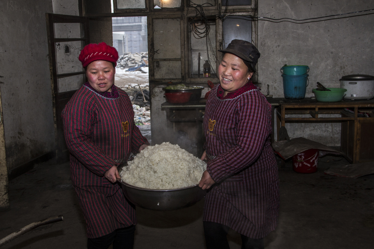 二位做饭师傅在往屋里端米饭.
