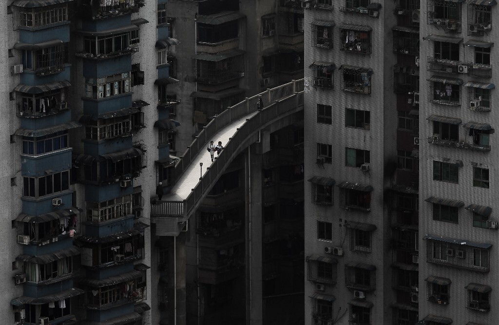 2010年4月,重庆渝中区解放东路,市民在楼宇的廊桥间经过。这里是重庆有名的上下半城,穿行于这些建于上世纪八九十年代的高大楼宇中,1楼你可以出门去破败的下半城吃冰粉凉虾,8楼你可以去解放碑CBD依偎繁华。