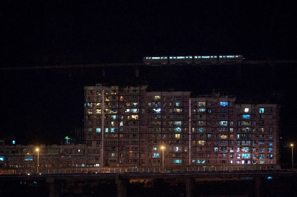 2015年10月16日,重庆渝中区牛角沱,黑夜里的轻轨犹如御空而行,从居民楼上空“飞”过。重庆城的轻轨、汽车和轮渡构成城市交通的“海陆空”。