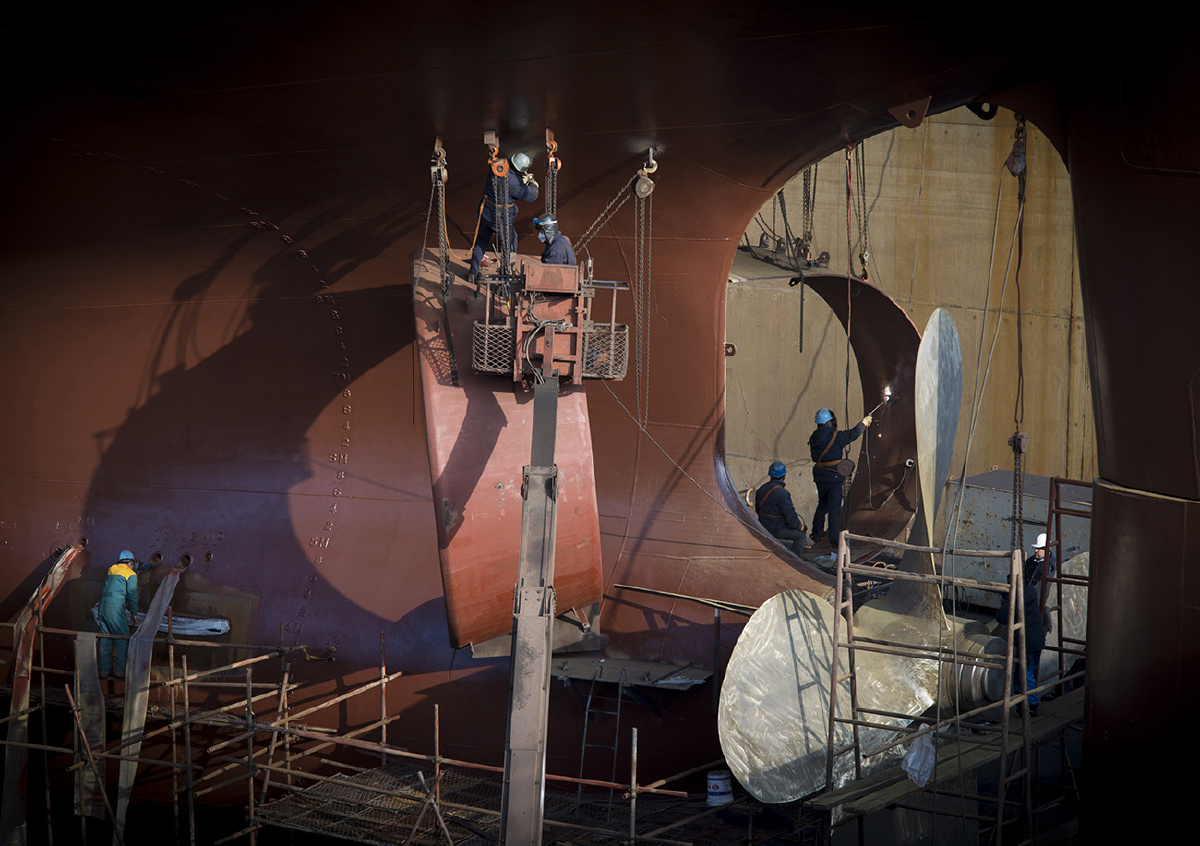 照片拍摄于河北省秦皇岛市山海关造船厂,表现了工人们对船体修护保养