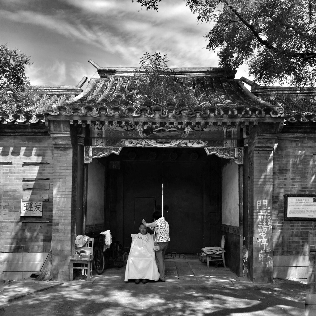 北京，摄政王马号门前，路边理发师傅在给一位老顾客理发