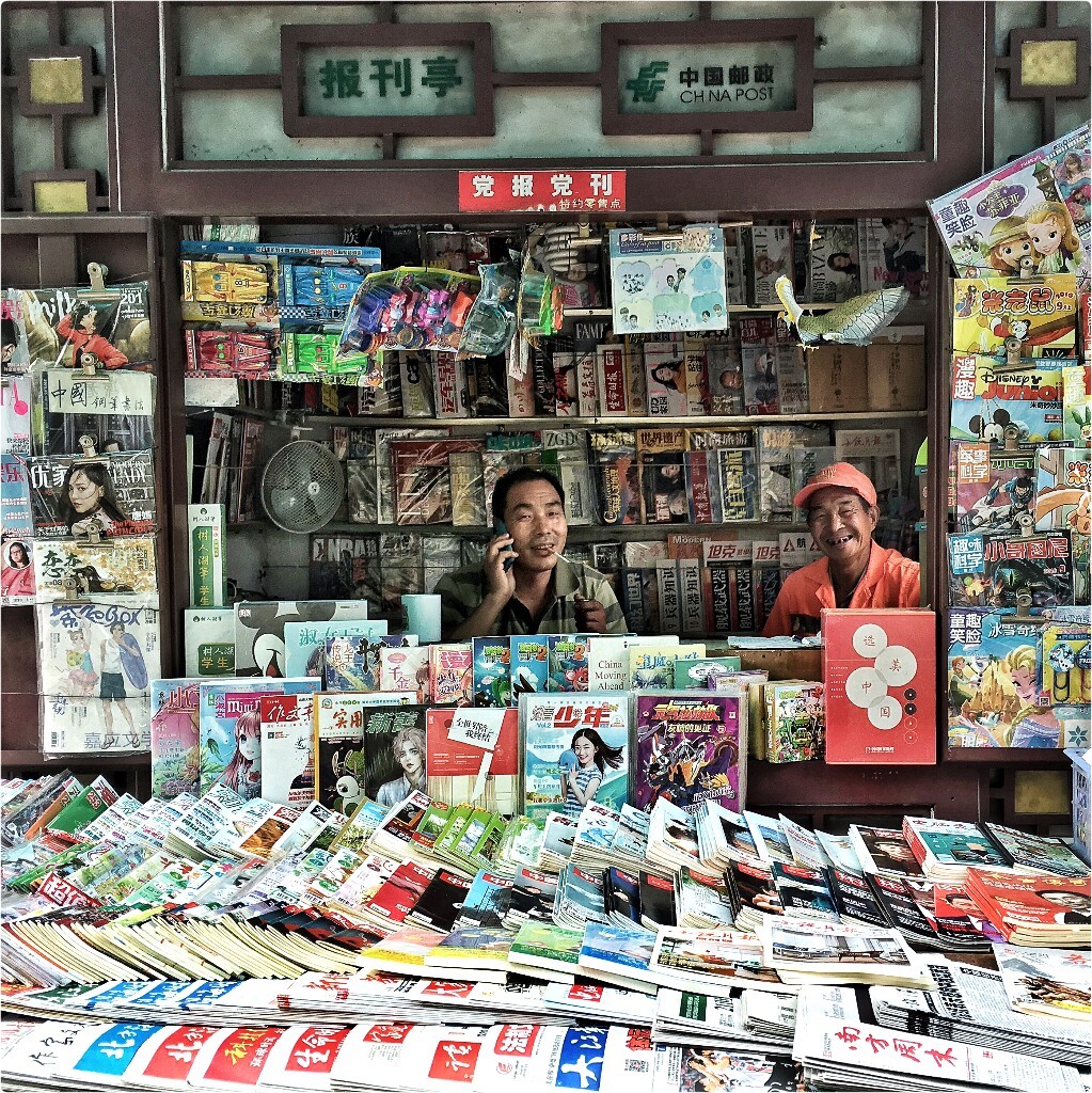 【手機隨拍】•《遠去報刊亭》<br />
他們散落在城市的街口，在高樓大廈的夾縫中殘喘。種類繁多的雜誌和報紙整齊的擺放著，但還是越來越少的年輕人會光顧。<br />
社會變得很快，但他們看上去還像是過去那副老氣橫秋得樣子，像與這個時代脫節了。<br />
以前三五個路口，就有一個報刊亭，但現在走好遠都難以看到一個。<br />
一個高聳建築成林的城市，沒有報刊亭，文化又能深厚多少？<br />
他們是它們是城市的文化底蘊，心靈的歸屬，等你去尋找。<br />
 ……