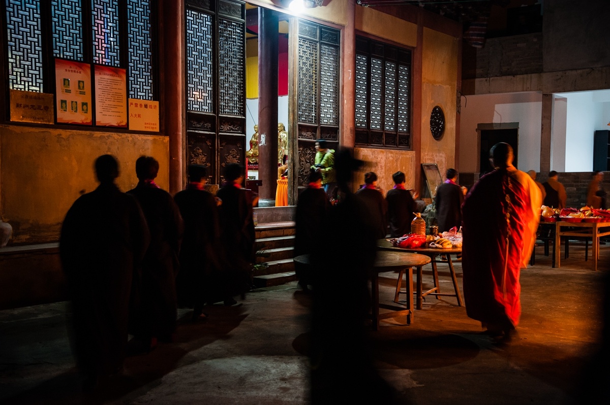 放生法事前,住持站在观音像旁,望向寺庙旁的稻田.法事结束,住持和