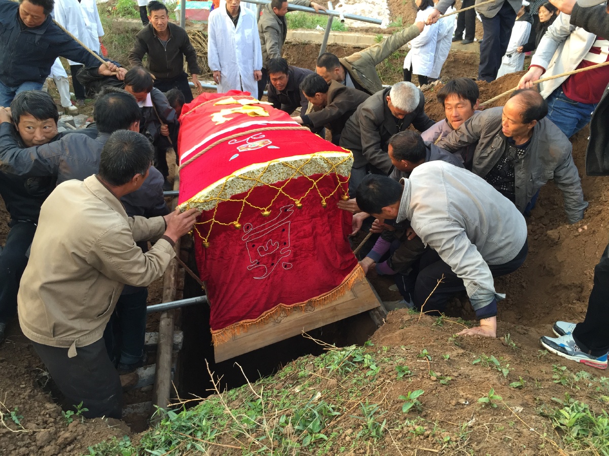 一众帮忙的村里人,合力用古老的办法把棺木慢慢放入墓穴.