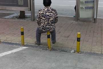 2014年6月3日，潍坊新华路，坐在隔离桩上休息的妇女