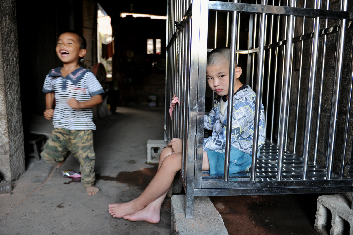 a1小孩被囚在铁笼里看着外面,隔壁家的孩子在周围玩耍