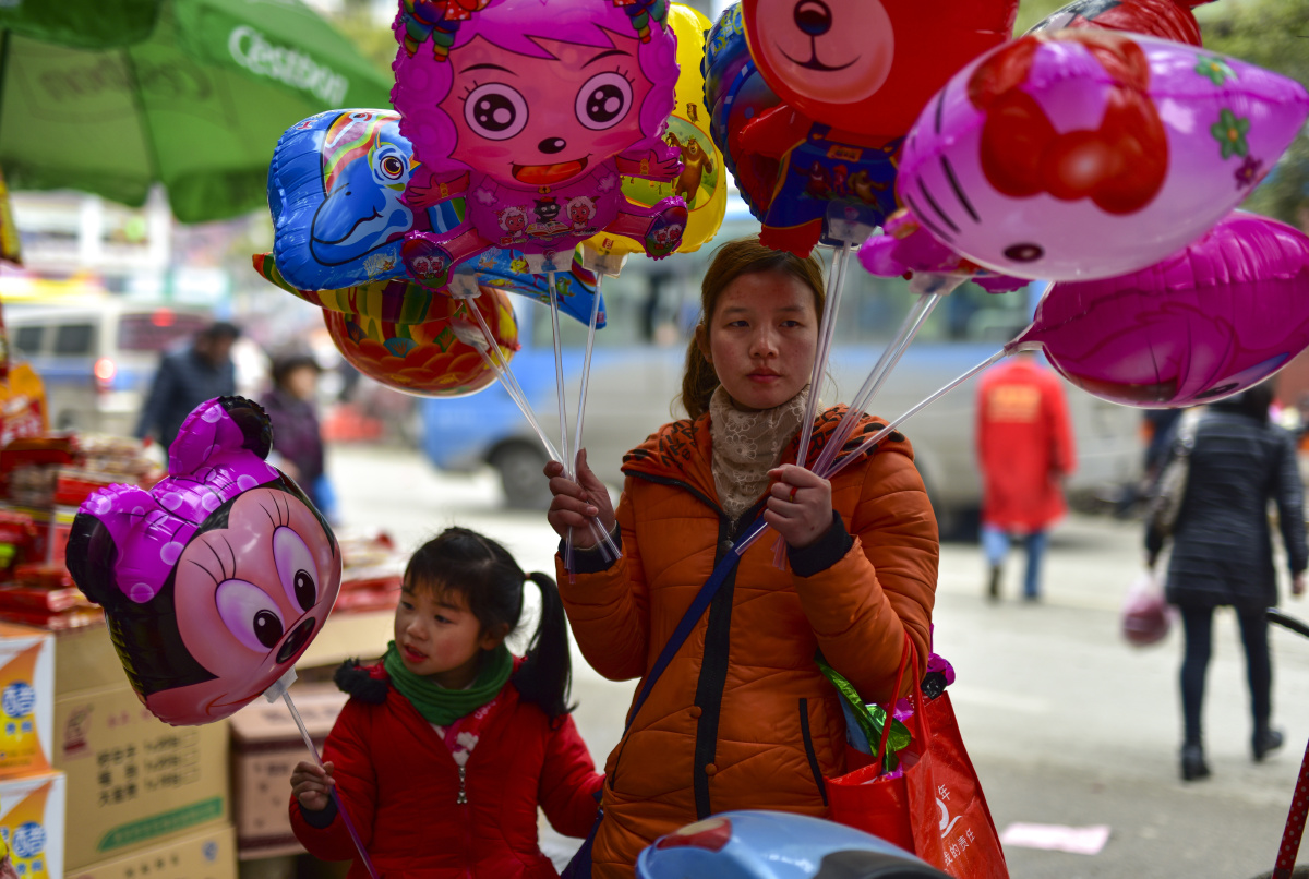 在湖南省武冈市春节前,一位小女孩在帮着妈妈卖卡通气球.