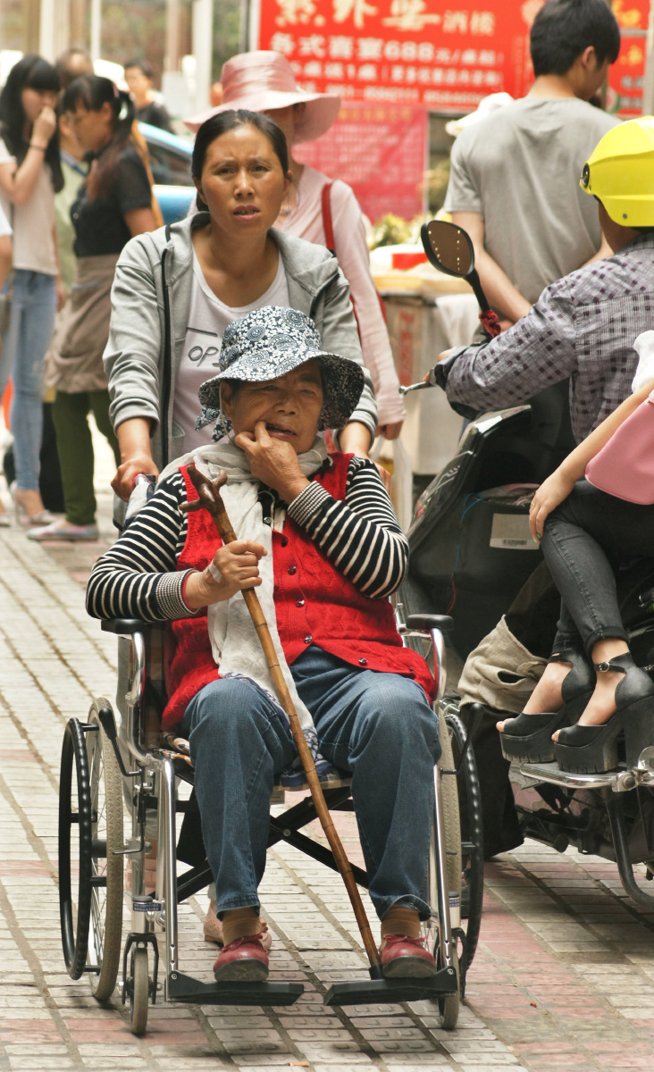 2016年5月7日,贵阳市都司路,一位看护推轮椅车将生病的老奶奶送回家